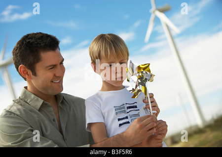 Boy (7-9) blowing toy windmill with father at wind farm Stock Photo