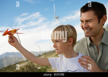 Boy (7-9) holding toy glider with father at wind farm Stock Photo