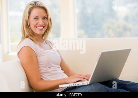 Woman in living room using laptop smiling Stock Photo