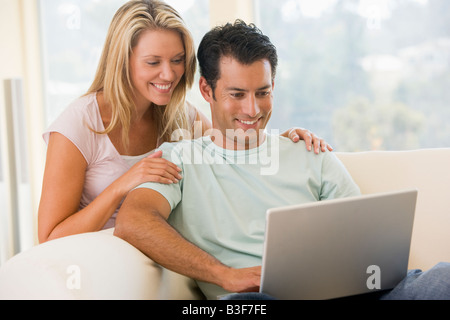Couple in living room using laptop smiling Stock Photo