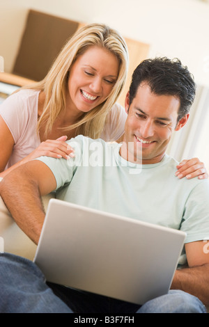 Couple in living room using laptop smiling Stock Photo