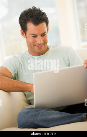 Man in living room using laptop smiling Stock Photo