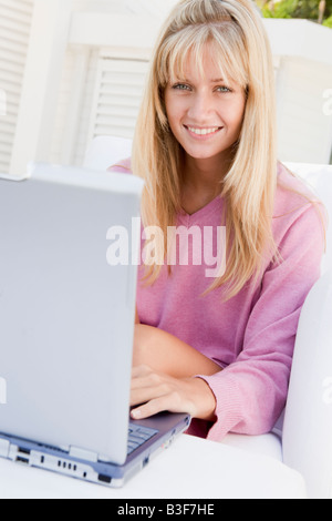 Woman on patio using laptop smiling Stock Photo