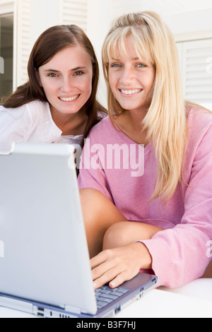 Two women on patio using laptop smiling Stock Photo