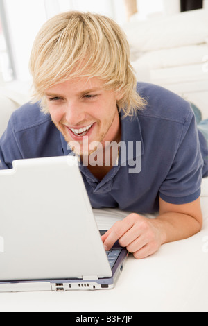 Man in living room with laptop smiling Stock Photo