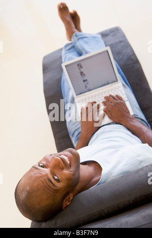 Man sitting in chair using laptop smiling Stock Photo