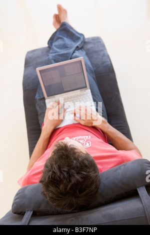 Man sitting in chair using laptop Stock Photo