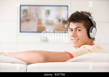 Man in living room watching television and wearing headphones Stock Photo