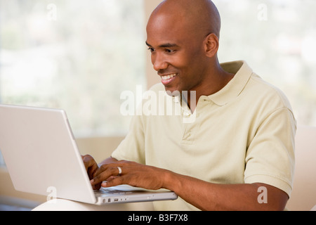 Man in living room using laptop and smiling Stock Photo