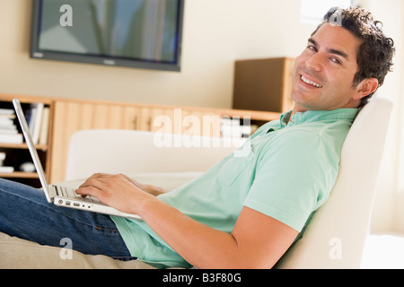 Man in living room using laptop smiling Stock Photo
