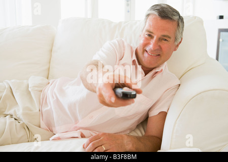 Man in living room using remote control smiling Stock Photo