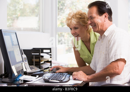 Couple in home office at computer smiling Stock Photo