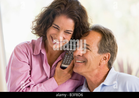 Couple indoors using telephone smiling Stock Photo