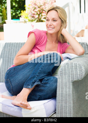 Woman sitting outdoors on patio smiling Stock Photo