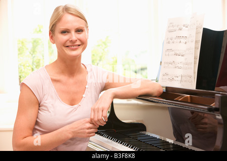 Woman sitting at piano and smiling Stock Photo
