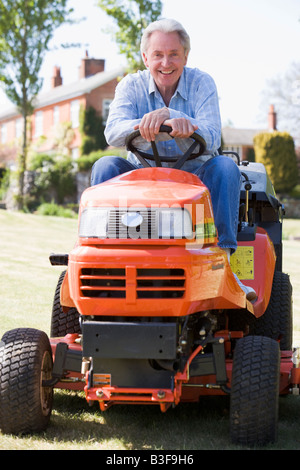 Man outdoors on lawnmower smiling Stock Photo