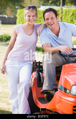 Couple outdoors with lawnmower smiling Stock Photo