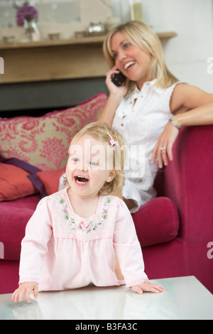 Mother using telephone in living room with baby smiling Stock Photo