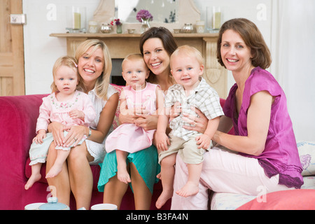 Three mothers in living room with babies smiling Stock Photo