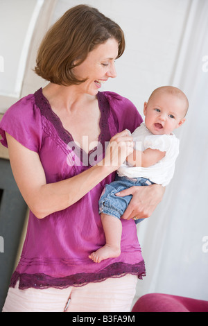 Mother in living room holding baby smiling Stock Photo