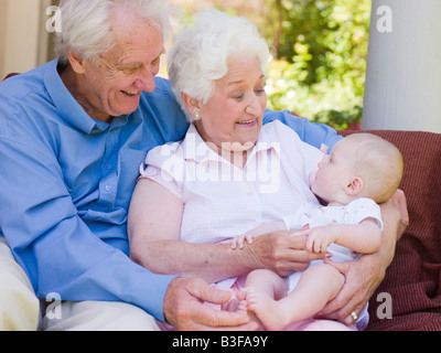 Grandparents outdoors on patio with baby smiling Stock Photo