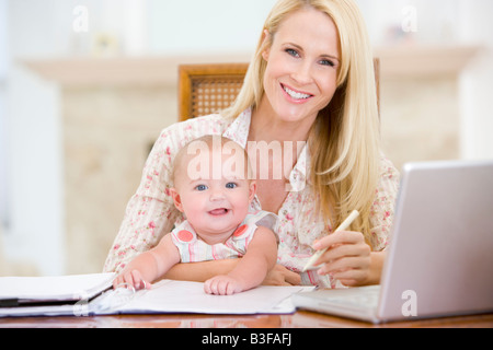 Mother and baby in dining room with laptop smiling Stock Photo