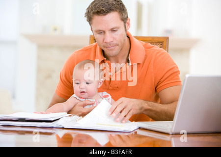 Father and baby in dining room with laptop Stock Photo