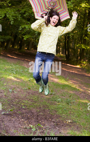 Woman outdoors jumping with umbrella smiling Stock Photo