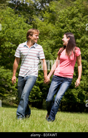 Couple walking outdoors holding hands smiling Stock Photo