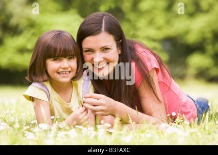 Mother and daughter lying outdoors with flower smiling Stock Photo