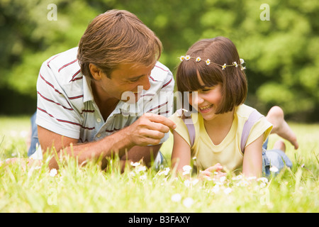Father and daughter lying outdoors with flowers smiling Stock Photo