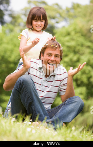 Father and daughter sitting outdoors with flowers smiling Stock Photo
