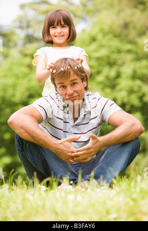 Father and daughter sitting outdoors with flowers smiling Stock Photo