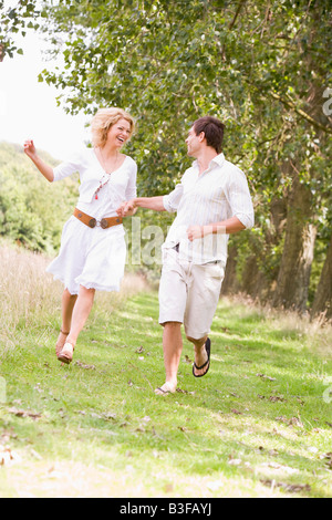 Couple running on path holding hands and smiling Stock Photo
