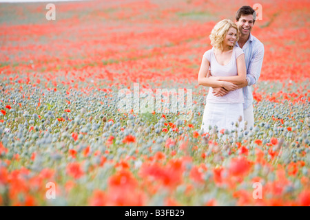 Couple in poppy field embracing and smiling Stock Photo