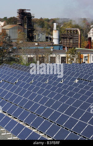 A solar powered electricity generating array is situated beside a factory complex in Brockton Massachusetts Stock Photo