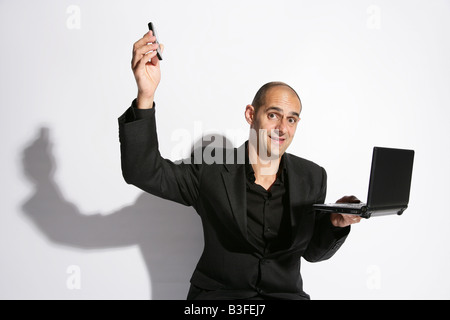 Man in a busines suit sat on a briefcase lap top on knee holding a telephone Stock Photo