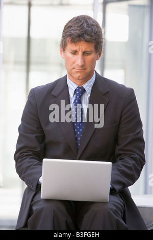 Businessman sitting in office lobby using laptop Stock Photo