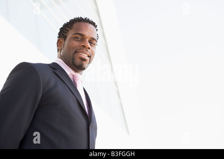 Businessman standing outdoors by building smiling Stock Photo