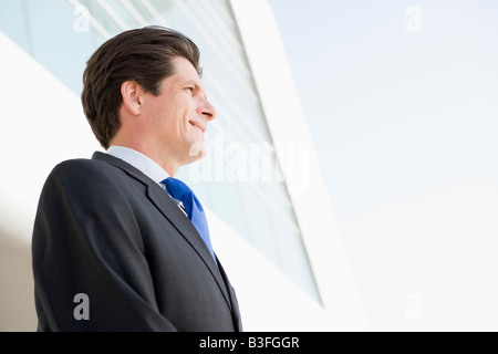 Businessman standing outdoors by building smiling Stock Photo