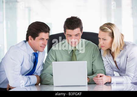 Three businesspeople in a boardroom looking at laptop Stock Photo