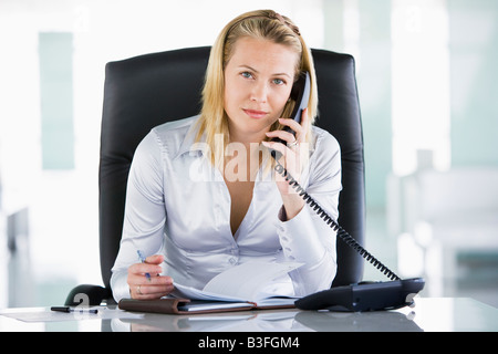 Businesswoman in office with personal organizer open on telephone Stock Photo