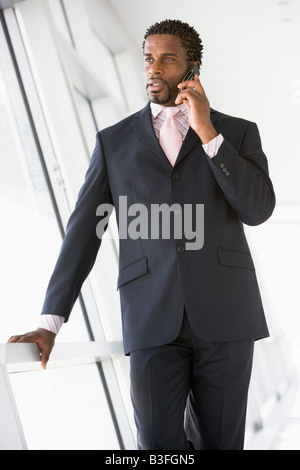 Businessman standing in corridor using cellular phone Stock Photo
