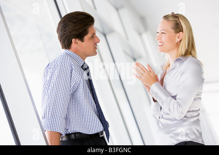 Businessman standing in corridor talking to smiling businesswoman Stock Photo