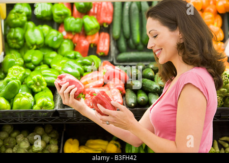 Woman shopping for bell peppers at a grocery store Stock Photo