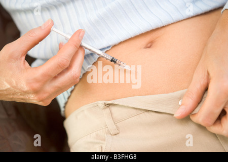 Woman injecting drugs to prepare for IVF treatment (selective focus) Stock Photo