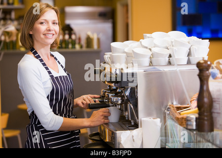 Woman making coffee in restaurant smiling Stock Photo