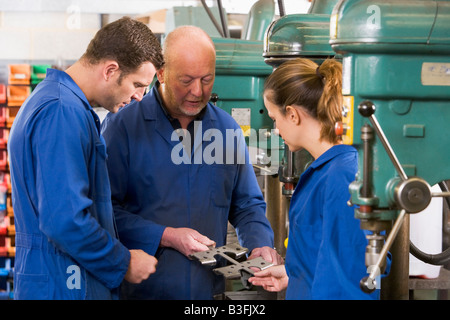 Three machinists in workspace by machine talking Stock Photo