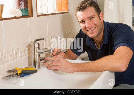 Plumber working on sink smiling Stock Photo