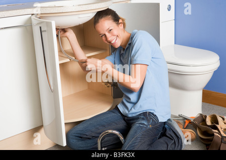 Plumber working on sink smiling Stock Photo